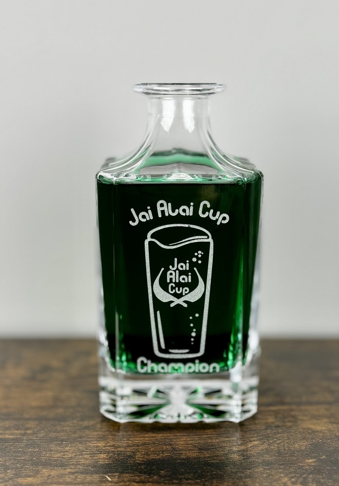Personalized engraved glass decanter filled with green liquid